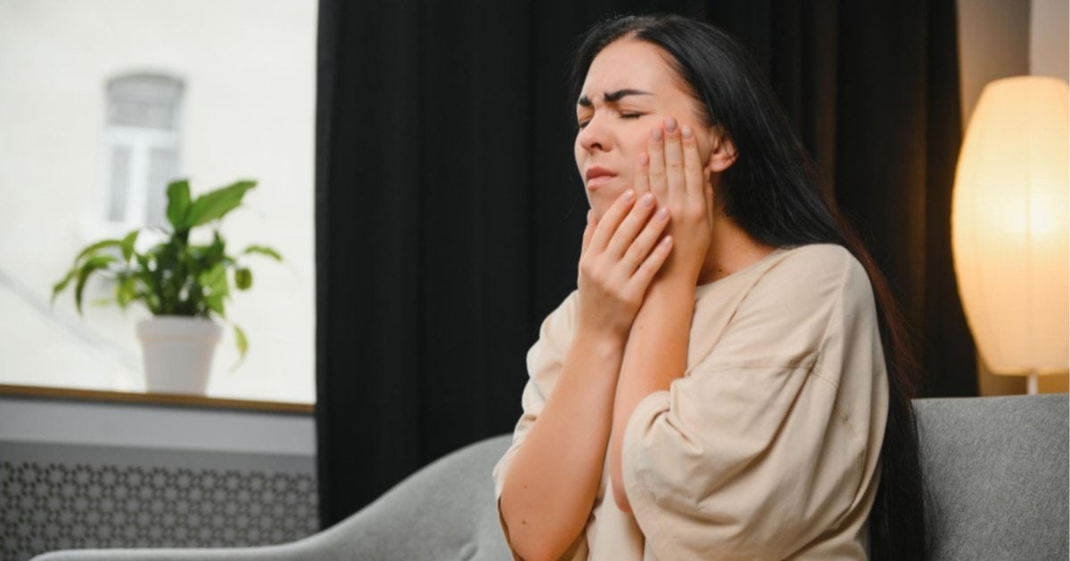 person holding their jaw in discomfort a common presentation of a toothache in Gordon