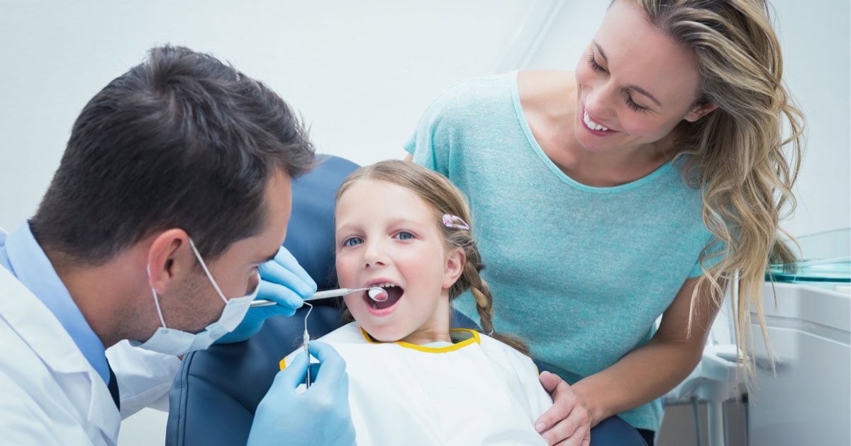 Dentist examining a child’s teeth with a parent nearby in Gordon