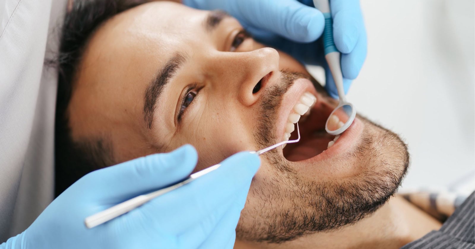 Dentist examining a patient’s teeth with a dental mirror in Gordon